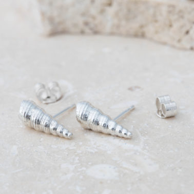 A pair off silver earring studs, cast from cone shells on grey stone.