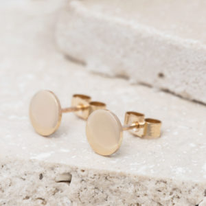 sleek gold circle studs shown on white stone