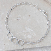silver chain bracelet with three connected silver rings, shown on grey stone plate